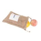 A burlap sack with a white label, partially open, revealing an orange and a peach spilling out.