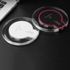 Two round wireless chargers are on a black surface near a laptop. One charger is white with a transparent edge, and the other is black with a red outline. Both have FANTASY Wireless Charger printed on them.