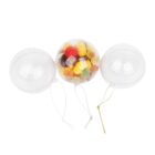 Three transparent plastic ornament baubles are shown. The left and right baubles are empty, while the central bauble is filled with assorted colorful candies. Each bauble has a string attached for hanging.