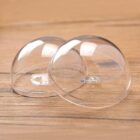 Two clear, half-sphere plastic domes placed upside down on a wooden surface. The domes have a smooth, glossy finish and are positioned slightly overlapping each other.