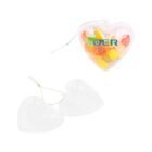 A heart-shaped clear plastic container with candies inside, featuring a blue logo. Next to it are two empty, separate halves of the same type of heart-shaped container. Both have a string for hanging.
