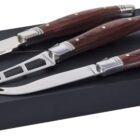Three cheese knives with wooden handles on a black rectangular box. The knives include a spreader, cleaver, and fork-tipped knife, each with a shiny stainless steel blade.