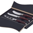 A set of three cheese knives with wooden handles is displayed in an open black box. The knives have different blade designs, suitable for various types of cheese. The interior of the box is fitted to hold each knife securely.