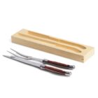 A carving knife and fork with wooden handles are placed in front of an open wooden box designed to hold them.