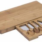 A rectangular bamboo cheese board with a hidden drawer slid open, revealing four assorted cheese knives with wooden handles. The smooth surface of the board highlights its sleek and natural design.