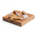 A wooden cheese board set with a drawer holding four cheese tools on top: a cheese knife, a fork, a spreader, and a chisel, each with a stainless steel blade and wooden handle.