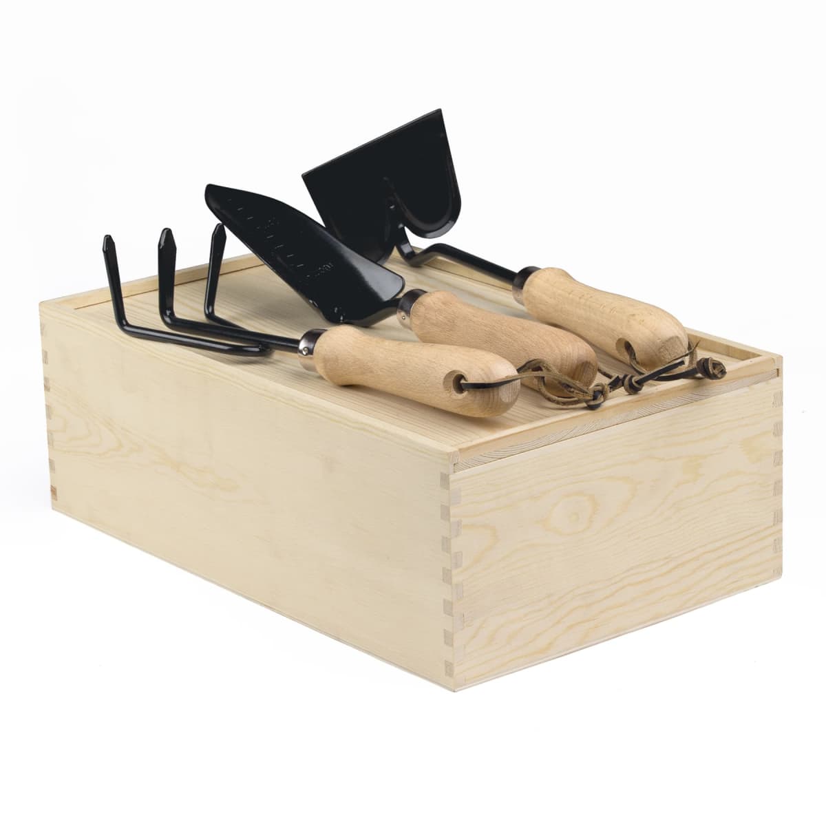 A set of gardening tools including a trowel, rake, and spade with wooden handles rests on a wooden box, showcasing neatly arranged equipment for gardening tasks.