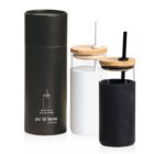 A black cylindrical packaging is next to two glass bottles with bamboo lids and straws. One bottle has a black sleeve and straw, the other has a white sleeve and straw. The packaging displays the words po di fame little hungry.