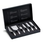 A black box with a set of five stainless steel cheese knives, each with a different blade shape. The box lid displays illustrations and descriptions of the knives: open work blade, cleaver, fork-tipped spear, spreader, and parmesan knife.