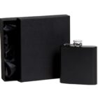 A sleek black flask with a silver cap stands next to an open black gift box lined with satin. The box is displayed on a plain white background, showcasing a minimalist and elegant design.