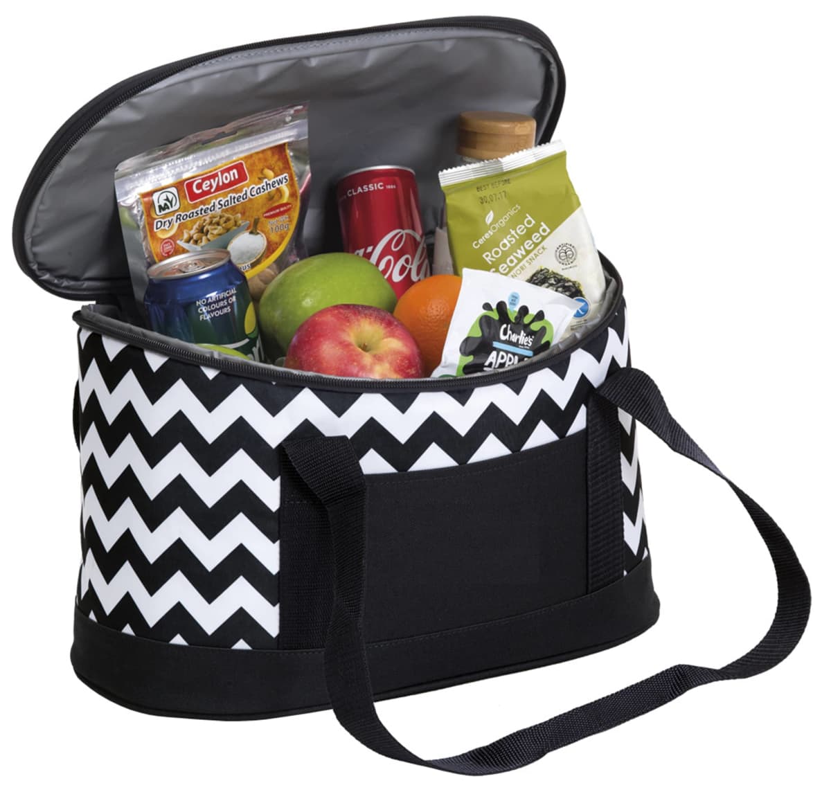 A black and white zigzag-patterned cooler bag is open, revealing its contents: a can of Coke, packets of cashews, a juice bottle, an apple, and a lemon. The bag has black handles and a front pocket.