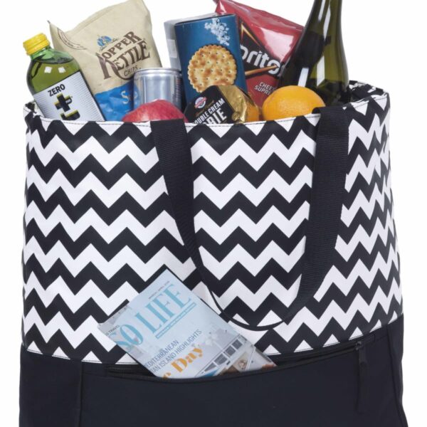 A black and white zigzag-patterned tote bag filled with groceries, including a bottle of wine, tortilla chips, canned drink, cereal, and fruits. A magazine is tucked into an outer pocket of the bag.