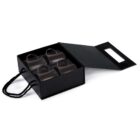 A black gift box with a handle, containing four black ceramic espresso cups, each with a small handle. The box has a matching black lid, partly open to reveal the cups inside.