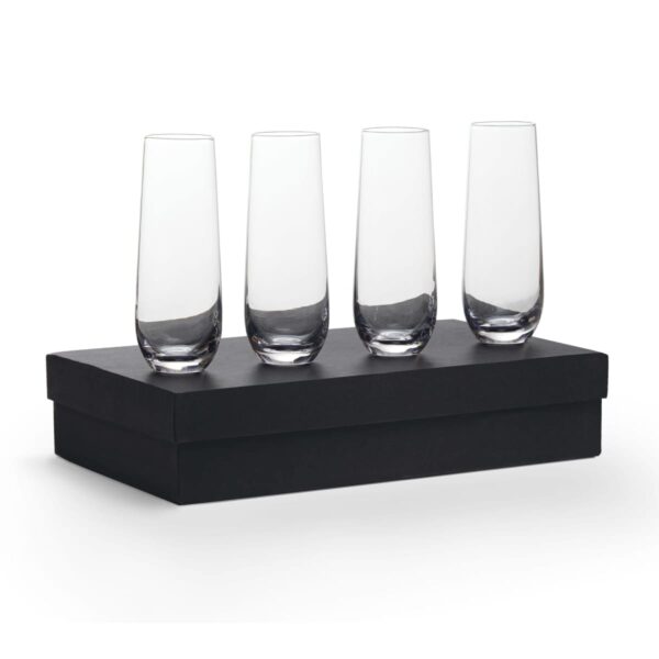 Four empty, tall, clear champagne glasses are neatly arranged on a closed black rectangular box against a plain white background.