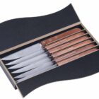 A box of six serrated steak knives with wooden handles, neatly arranged in individual slots. The box has a wavy black design, contrasting with the polished silver blades and brown handles.