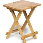 A small wooden folding table with a square top and crossed legs. The table is made of light-colored wood and features notches on two sides for easy carrying.