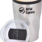 A stainless steel travel mug with a logo reading Aerial Express is filled with a frothy beverage. A clear plastic lid is propped beside it.