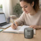 Woman studying at a desk with a notebook, laptop, and Swiss Peak Bass Speakers branded Your Logo Here.