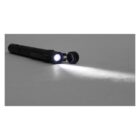 A black flashlight lying on a flat surface emits a bright white beam of light.