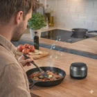 A man cooks vegetables while listening to music on Yukon Bluetooth Speakers in the kitchen.