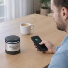 Man charges phone on Zaragoza Speaker Wireless Chargers; coffee cup and logo visible nearby.