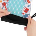 Hands holding a fabric organizer with a black opening. The cover features a blue and white diamond pattern with illustrations of household items like cups and teapots along the edge.
