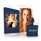 Exhibit setup with large photo displays and a counter labeled Jewelry. The displays feature a womans portraits. A man stands behind the counter. The setup includes labeled sections for arm lights and various product codes.