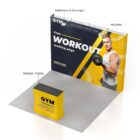 A gym promotional booth featuring a large backdrop with a muscular person in workout attire. Text reads Free Workout Landing Page. A yellow counter displays GYM Free Weekend Trial! and light fixtures are mounted above.