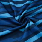Close-up of a fabric with a pattern of diagonal stripes in various shades of blue. The fabric is twisted at the center, creating a spiral effect that highlights the texture and vibrant color contrasts.
