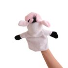A hand is holding a cow puppet against a plain white background. The puppet has a pink face, black ears, and black spots on its arms.