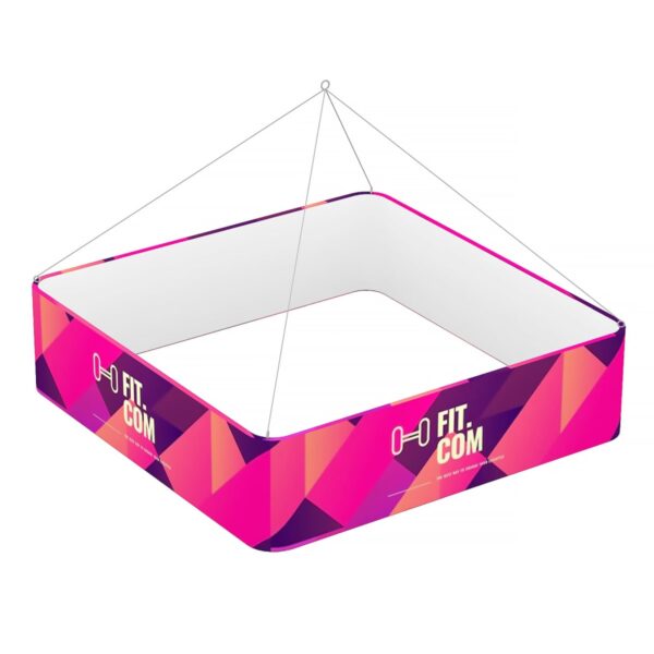 A square hanging banner with vibrant pink and purple geometric patterns. It features the text FIT.COM with a dumbbell icon. The banner is suspended by wires from each corner.