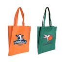 Two tote bags are displayed. The orange bag features a cow graphic with the text Devondale and Australian Dairy. The green bag has a bird design with the text Coltivi. Both bags have matching handles.