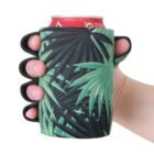 A hand holds a can of soda wrapped in a green koozie designed to look like a boxing glove with a palm leaf pattern on it.