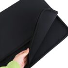A persons hand holding the open flap of a black laptop sleeve against a white background. The sleeve appears to be made of a soft, protective material, and the persons sleeve is light green.