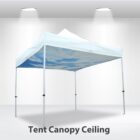 A white canopy tent with a blue sky design and clouds printed on the ceiling is set up indoors. The floor is white, with two ceiling spotlights illuminating the area. Text below reads, Tent Canopy Ceiling.