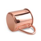 A shiny copper mug, with a smooth and polished surface, is lying on its side. The handle is attached securely to the mug, which has a cylindrical shape and reflective copper finish.