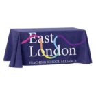 A dark blue tablecloth covers a rectangular table. The text East London Teaching School Alliance is printed in white, accompanied by a colorful, wavy line design.