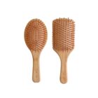 Two wooden hairbrushes with natural bristles. One is oval-shaped, and the other is rectangular. Both have smooth wooden handles with a logo inscribed on them. The brushes are placed on a white background.