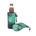 A brown glass bottle in a green leafy-patterned neoprene sleeve, standing upright. Next to it lies a matching zipped sleeve with a small drawstring toggle. The design features large tropical leaves on a dark background.
