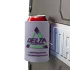 A red can in a light gray Delta Fluidpower koozie is magnetically attached to a metallic surface. The koozie features a green and purple triangular logo with the website and email address printed below.