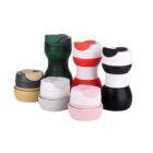 A collection of collapsible cups in various colors, including black, red, white, green, beige, and pink. The cups have a compact, stackable design with silicone lids and bodies.