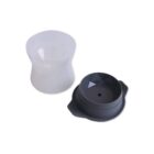 A translucent plastic cup and a black silicone lid with geometric design are shown. The lid has a small hole in the center and side grips. Both items are placed against a plain white background.