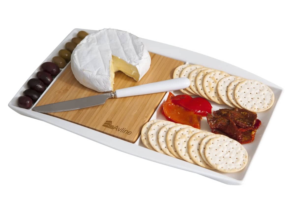 A cheese platter with a wheel of brie, a knife, assorted olives, slices of red pepper, sun-dried tomatoes, and crackers arranged on a wooden board with a white tray.