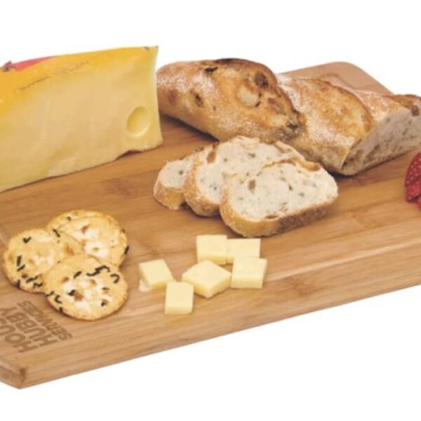 A wooden board with a wedge of cheese, bread, slices of bread, crackers, cheese cubes, and two strawberries.