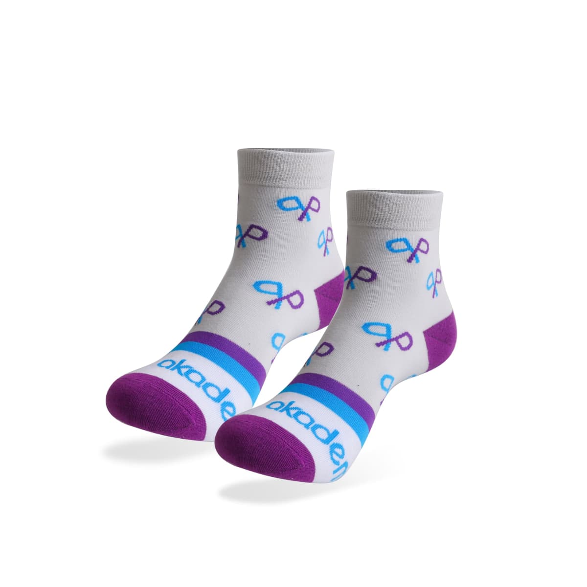 White socks with purple heels and toes feature a print of purple and blue ribbons. The socks have a blue and purple band around the ankle with part of a word in blue letters.