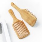 Two wooden hair brushes with natural bristles are placed on a white surface. One brush is facing up, showing the handle and bristles, while the other is facing down, displaying its smooth back.
