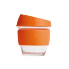 A clear glass cup with an orange silicone band around the middle and a matching orange lid. The design is simple and modern.