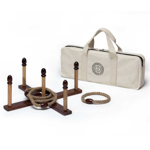 A wooden ring toss game set with a cross-shaped base and five pegs. Three rope rings are included. A beige carrying bag with handles is behind the game set.