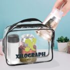 A clear toiletry bag with cosmetics and a hand placing in a tube, on a light blue background.