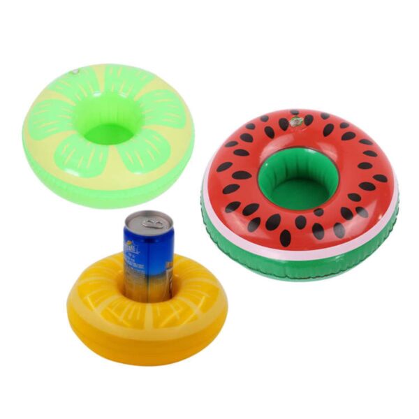 Three inflatable drink holders are displayed: a green one resembling a lime, a red one with black seeds resembling a watermelon, and a yellow one resembling a pineapple. The yellow holder is shown with a beverage can inside.